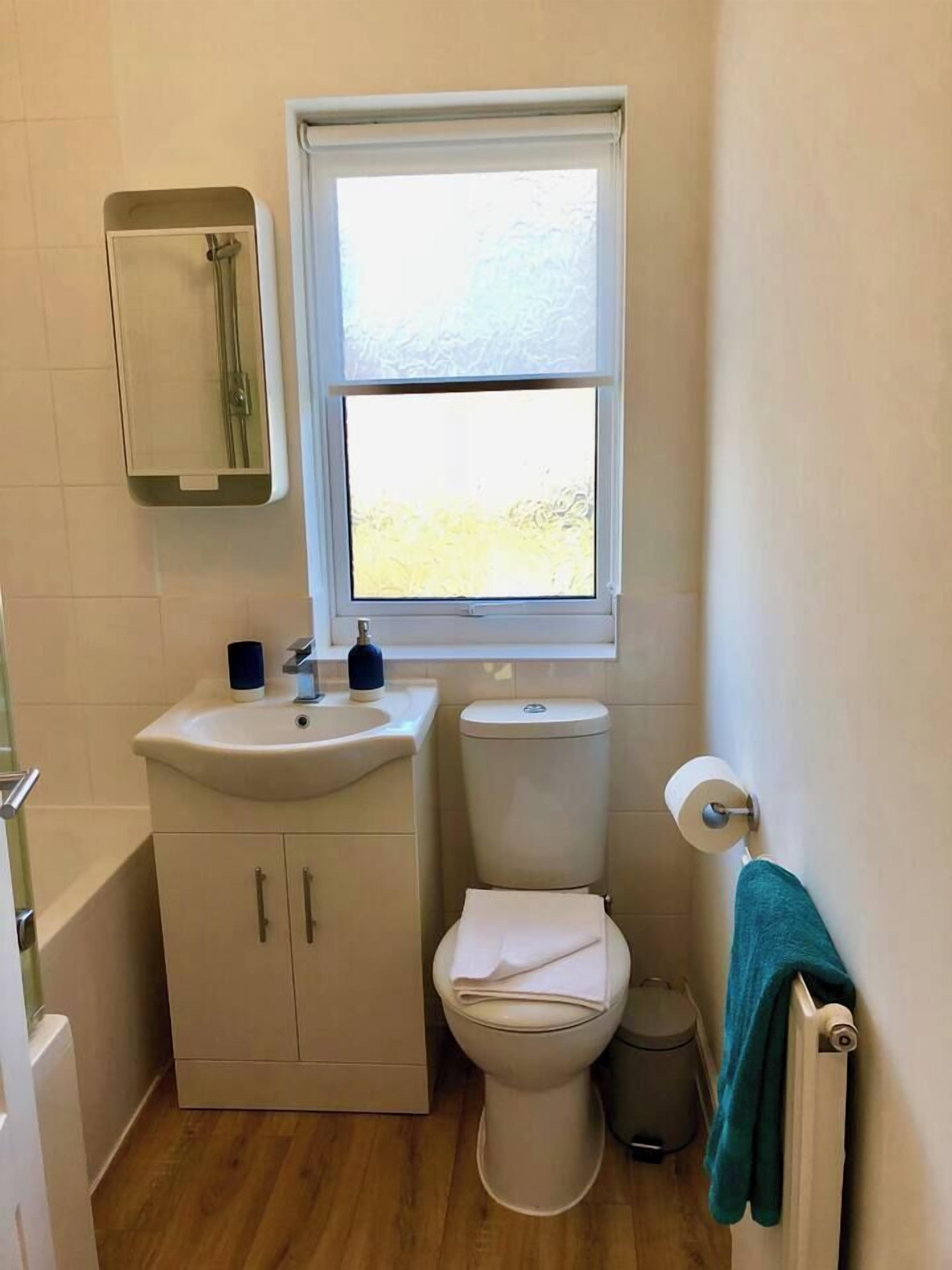 Baño pequeño con inodoro, lavamanos y ventana.