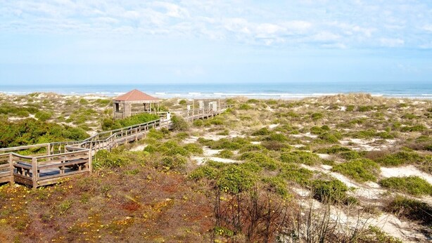 A coastal area with a wooden boardwalk leading to a gazebo-like structure. - Shell Shack - St. Augustine Beachside Resort Condo (St. Augustine)