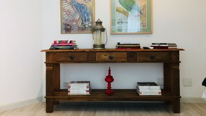 A wooden console table with books, a red lamp, and two framed artworks.