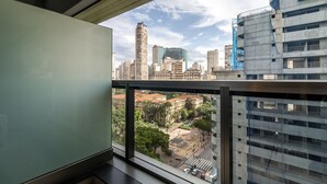 Uitzicht vanaf een hoog gebouw met balkon, over een stadsgezicht met diverse gebouwen, waaronder een opvallende wolkenkrabber en een gebouw met een blauwe gevel.