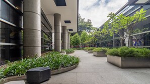 Een modern gebouw met grote betonnen pilaren, een centrale binnentuin met plantenbakken en een glazen gevel.