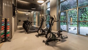 Een sportschool met spinningfietsen, loopbanden en een gewichtrek.