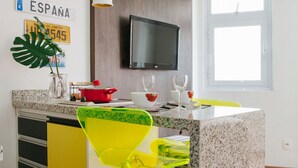 A modern kitchen with a granite countertop, a TV mounted on the wall, and a window providing natural light. - AV504 - Design Studio in Avanhandava Street (São Paulo)