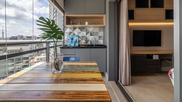 Una cocina moderna con vista a la ciudad, una mesa de madera con una planta y un televisor montado en la pared.