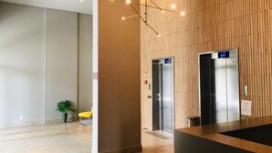 Un vestíbulo moderno con dos ascensores, una recepción y una planta en maceta.