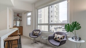 Una cocina moderna con taburetes de bar, una pequeña mesa redonda y dos sillas con cojines estampados.