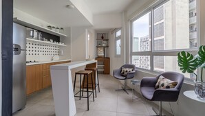 Una cocina moderna con barra, taburetes de madera y un amplio ventanal con vistas a la ciudad.