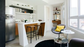 Una cocina moderna con una isla central, taburetes de bar y un comedor con una silla y una mesa.