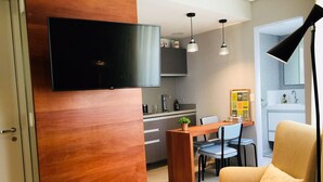 Una cocina moderna con televisor de pantalla plana, armarios de madera e iluminación colgante.