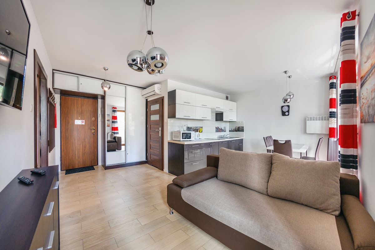 Ein modernes Wohnzimmer mit einer Couch, einem Holzschrank und einem Küchenbereich im Hintergrund.