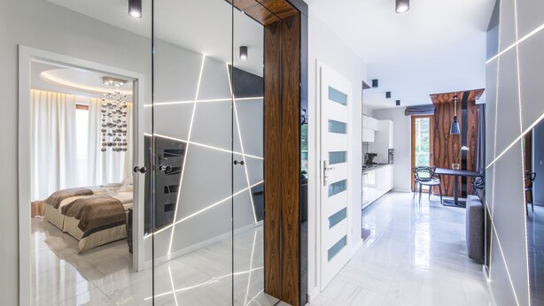 Um interior moderno com divisória de vidro, porta de madeira, área de cozinha e espaço de jantar.