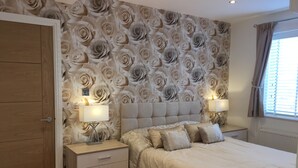 Una camera da letto con un letto grande, due comodini con lampade, un'armadio in legno e un motivo floreale sul muro.
