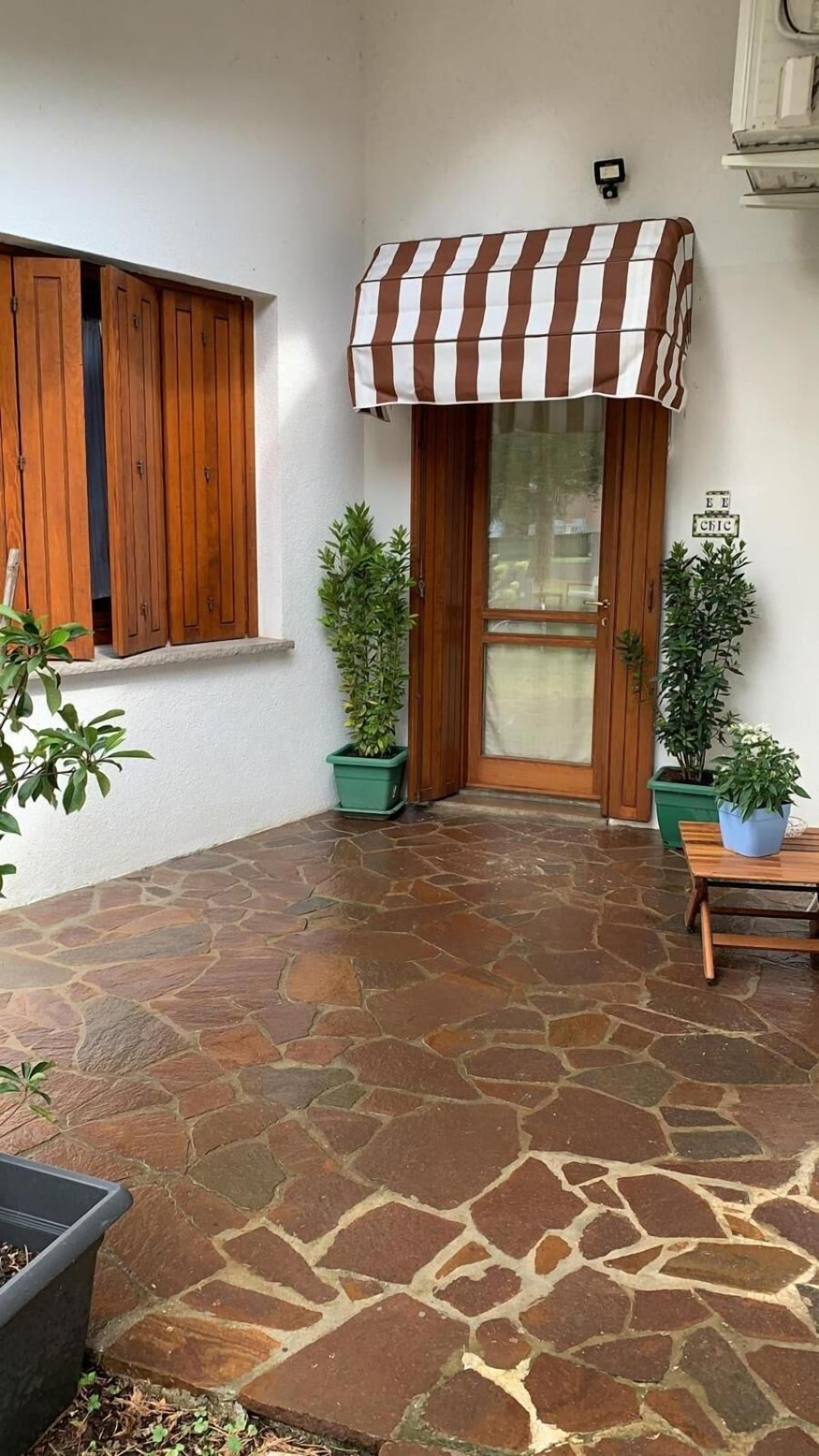 A stone-floored patio with a wooden door and a striped awning.
