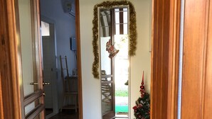 Un pasillo con puerta de madera, un espejo, un pequeño árbol de Navidad y un reloj en la pared.