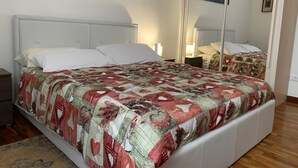 Un dormitorio con cama, mesitas de noche, un espejo y obras de arte en las paredes.