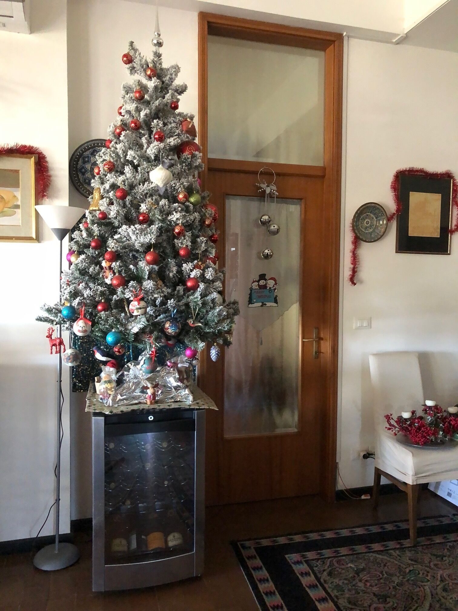 A living room with a decorated Christmas tree, a door with a frosted glass panel, and a framed picture on the wall.