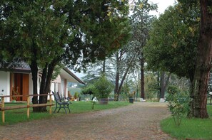 A pathway leading to a building with a wooden fence and benches. - B&B Chic (Premariacco)