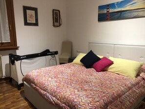 A bedroom with a bed, a chair, and a painting of a bridge. - B&B Chic (Premariacco)