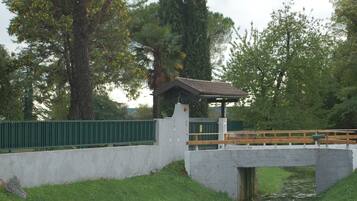 Un ponte in cemento con un piccolo riparo, immerso nel verde e circondato da alberi.