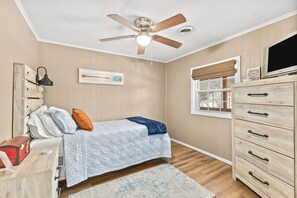 A bedroom with a bed, a dresser, a ceiling fan, a window with blinds, and a painting on the wall.