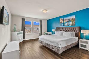Une chambre à coucher avec un grand lit, une table de chevet, une commode et une fenêtre avec des rideaux.
