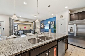 A modern kitchen with granite countertops, stainless steel appliances, and pendant lighting. - Disney near 5BR Pool Townhome w Theme Rooms (Kissimmee)