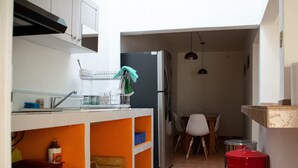 A compact kitchen with a refrigerator, a sink, and a dining area with chairs.