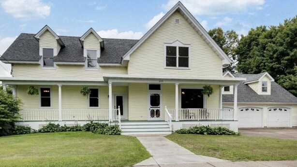 A two-story house with a front porch, a garage, and a well-maintained lawn.