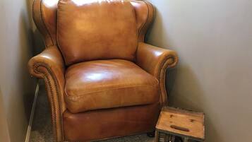 Een bruine leren fauteuil met een houten bijzettafeltje ernaast.