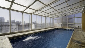 Sisäuima-allas, josta avautuu näkymä kaupunkiin suurten ikkunoiden kautta.