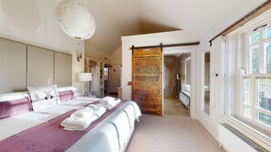 A bedroom with a large bed, a wooden door, and a view of the outside.