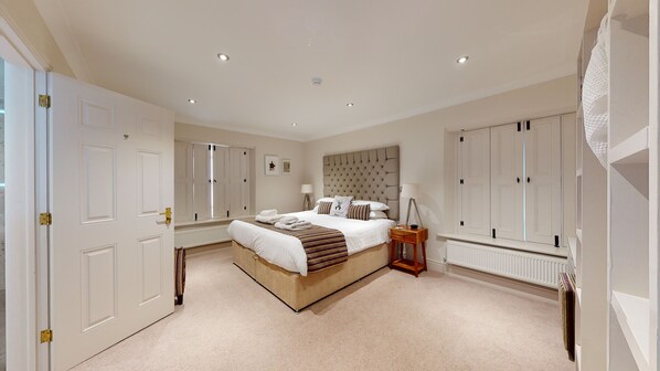 Une chambre spacieuse avec un grand lit, une table de chevet, un radiateur et une armoire.