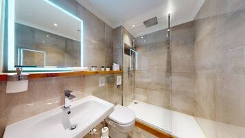 A modern bathroom with a glass-enclosed shower, a white sink, and a toilet.