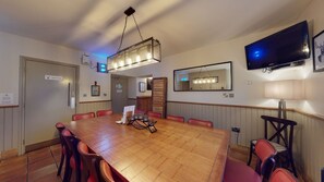 A conference room with a large wooden table, red chairs, a television, and a mirror on the wall.