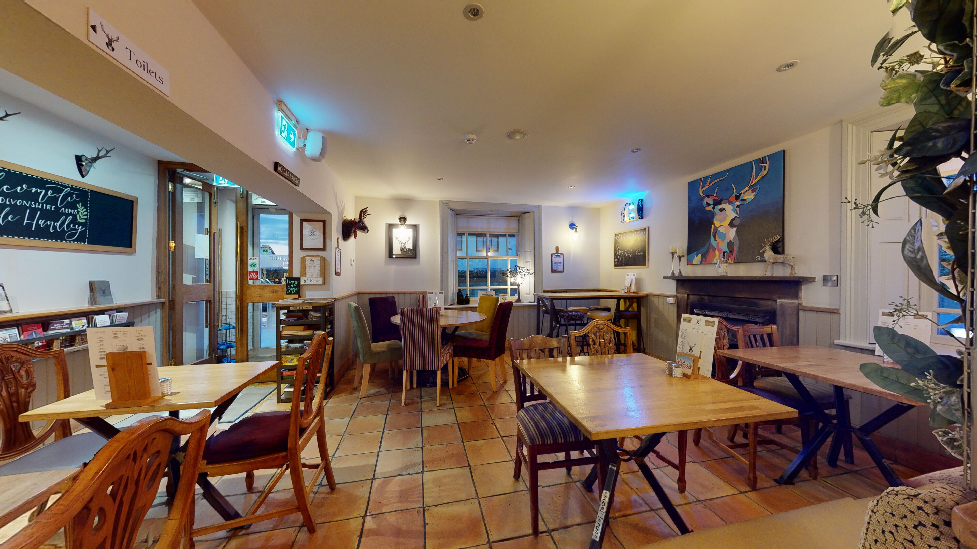 A cozy restaurant with wooden tables and chairs, a chalkboard menu, and a fireplace.