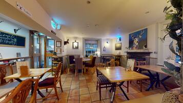 A cozy restaurant with wooden tables and chairs, a chalkboard menu, and a fireplace.