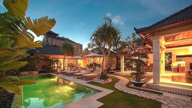 A well-lit outdoor pool area with lounge chairs and a stone pathway. - Villa Dayak Bali, a luxury tropical resort in the heart of Seminyak (Seminayk)