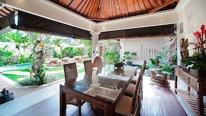 A dining area with a wooden ceiling, a glass table, and wicker chairs. - Villa Dayak Bali, a luxury tropical resort in the heart of Seminyak (Seminayk)