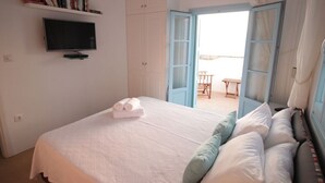 A bedroom with a bed, a TV, a wardrobe, and a balcony. - Beautiful beachfront property (Chora, Ios)