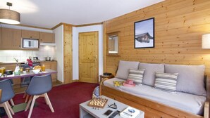 A cozy room with a wooden wall, a sofa, a dining table with chairs, and a kitchen area. - 300m from ski slopes, swimming pool, balcony, tv, ski locker, 28m², Notre Dame de Bellecombe (Notre-Dame-de-Bellecombe)