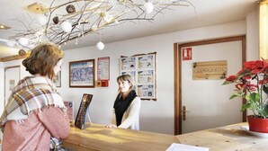 A reception desk with a wooden counter, a framed picture, and a potted plant. - 300m from ski slopes, swimming pool, balcony, tv, ski locker, 28m², Notre Dame de Bellecombe (Notre-Dame-de-Bellecombe)