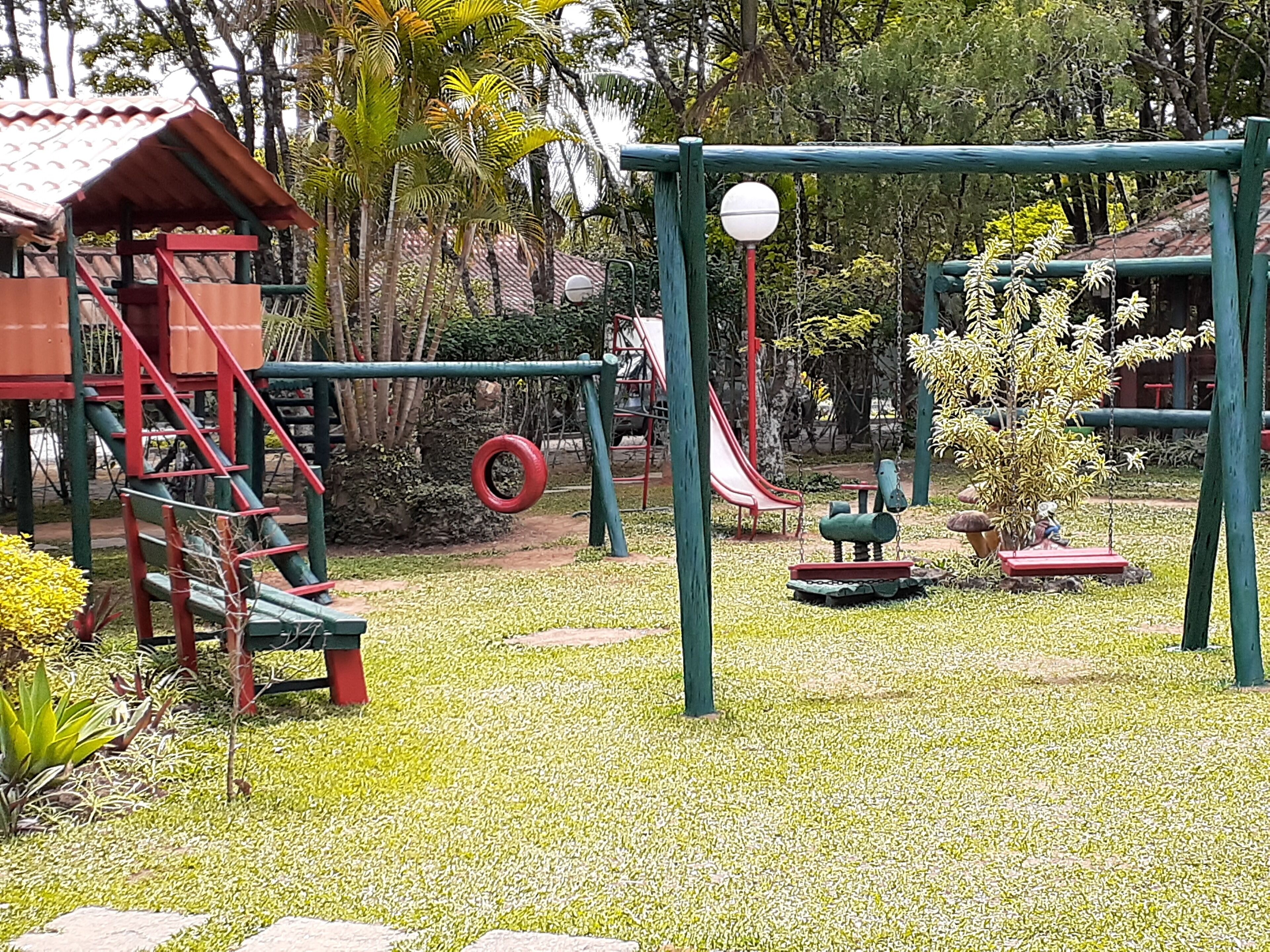 Un parque infantil con un tobogán rojo, columpios y una estructura para escalar.