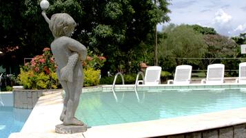 A stone statue of a figure holding a ball by a poolside.