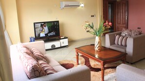 A living room with a sofa set, a coffee table, a TV, and a potted plant.