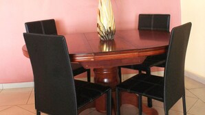 A dining table with four chairs, a vase with flowers, and a framed picture on the wall.