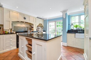 A kitchen with a central island, white cabinetry, and a Buddha statue.