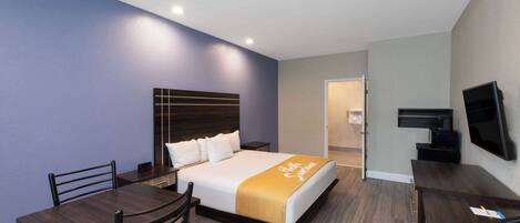 Una habitación de hotel con cama, escritorio, silla y televisor.