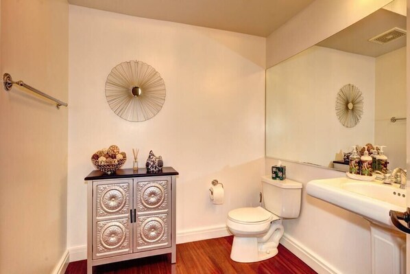 A bathroom with a white toilet, a vanity with a mirror, and decorative wall sconces.