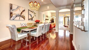 A dining area with a marble table and chairs, a chandelier, and abstract wall art.