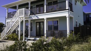 Ein zweistöckiges Haus mit Veranda, Treppe und Balkon.